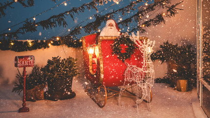 Santa Claus in his sleigh with a reindeer and a mailbox in a snowy scene
