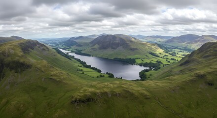 Panoramic aerial view showcases a lake surrounded by green hills, under a cloudy sky