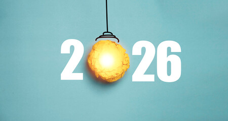 A glowing paper light bulb placed between the numbers 2026 represents a creative idea concept...