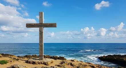 Wooden cross stands tall on a coastal cliff against a backdrop of the ocean and sky
