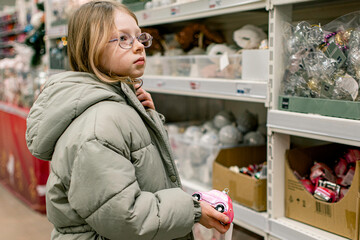 A girl in a store among Christmas decorations. Preparing for the New Year and Christmas. Buying decorations and gifts.
