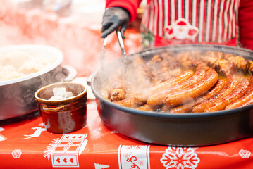 vendor fries meat and sausage on the grill in the city center at the Christmas market in Gdansk Poland