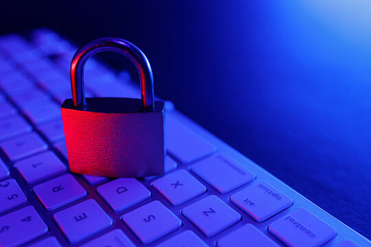 Cyber security illustrated with a padlock on a keyboard in a dimly lit environment