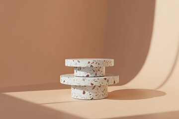 Minimalist stacked terrazzo pedestals casting soft shadows on a warm neutral background