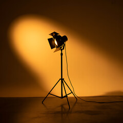 Professional studio spotlight with warm orange light illuminating a textured background