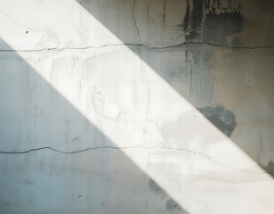 Diagonal sunlight beam illuminating textured concrete wall with cracks and shadows