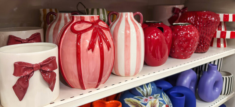 Bright ceramic vases and decor items in bold red, pink, and striped designs. Stylish pottery pieces displayed on a store shelf, perfect for home decoration and modern interior accents.
