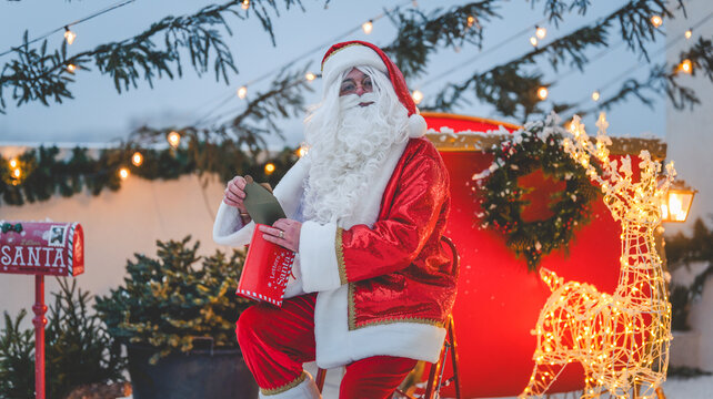 Santa Claus reading letters in a festive Christmas scene with reindeer and decorations