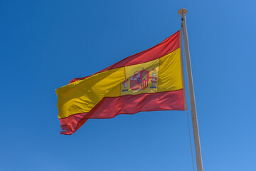 Flag of Spain waving in breeze with blue sky 