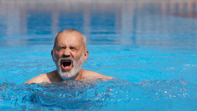 An adult man swims breaststroke in a swimming pool.