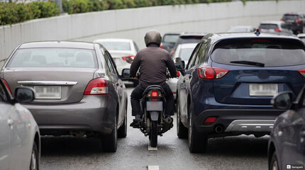 Motorbike between cars in traffic jam on crowded city road  