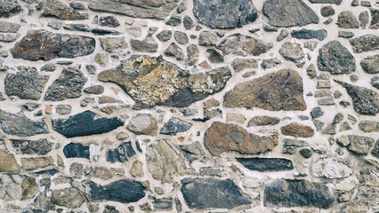 Rustic Natural Stone Wall Texture Background. Irregular Granite and Quartzite Rocks Pattern with Mortar Joints for Architectural and Historical Backdrop.