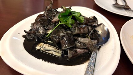 Stir fried black squid menu on the white dish , Thai food.