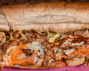 Long sandwiches with chicken breast, eggs, cabbage, cheese and dressing on plate