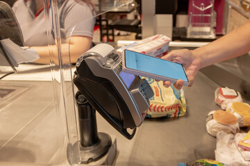 Customer using smartphone for contactless payment at checkout counter
