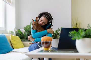 Woman embracing dog, working remotely from home