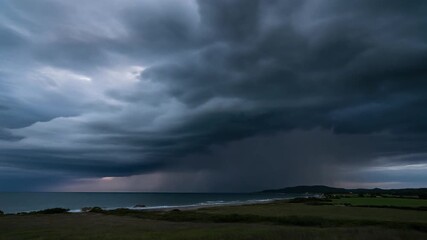 Stormy skies over a coastal landscape with rain falling on the ocean