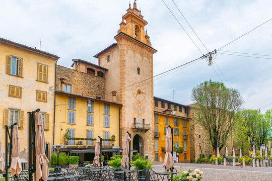 Charming square in Bergamo old town with clock tower, colorful buildings and outdoor cafe seating. Piazza Mascheroni in Citta Alta, Lombardy, Italy with Torre del Gombito. Italian architecture