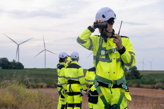 Workers monitor wind turbine operations near renewable energy site with modern technology - Powered by Adobe