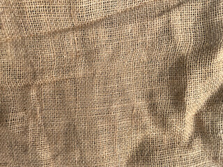 Natural burlap fabric close-up texture. Beige woven jute material with visible fibers and folds. Rustic background perfect for packaging design, crafts, textiles, eco style, and mockups.