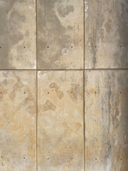 Weathered beige concrete wall with vertical and horizontal tile divisions, subtle stains, scratches, and natural texture. Neutral industrial background suitable for design, architecture, and material 