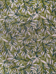 Fabric texture with a repeating botanical pattern of hand-drawn leaves in green and white tones. Natural organic background suitable for textiles, wallpapers, and decorative design.