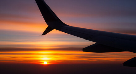 Spectacular Aerial View of Sunset from a Commercial Airplane Window.
A breathtaking photograph captured from an airplane window, showcasing the dramatic silhouette of the aircraft wing against