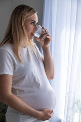 A pregnant woman drinks water. Selective focus.