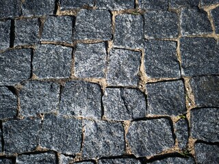 Dark paving stone roadway. Gray cobblestone pathway