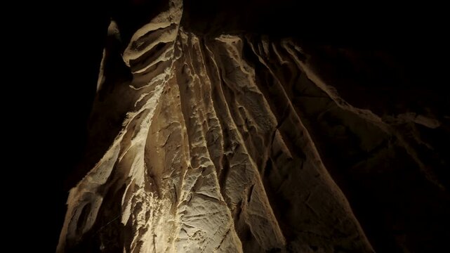 Natural limestone cave texture with stalactites and stalagmites in darkness. Mysterious underground tunnel in Thailand.