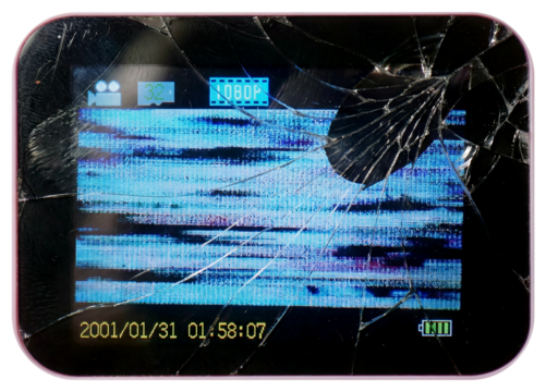 Close-up of a broken digital camera or handheld device screen displaying distorted static, glitch artifacts and a cracked glass surface.