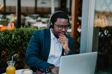 Focused black businessman working remotely with laptop outdoors