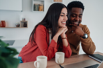 Diverse couple enjoying online content on laptop at home