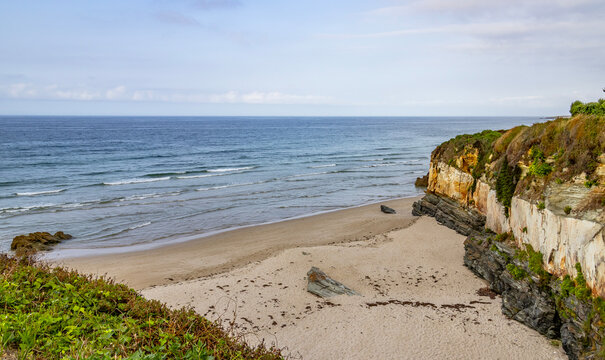 Empty sand cove with sedimentary rock cliffs on the Atlantic coast of Northern Spain.