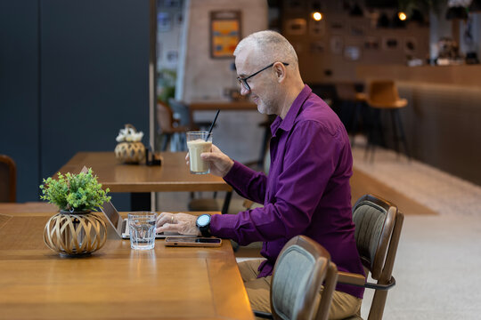 Mature man working remotely with laptop enjoying coffee