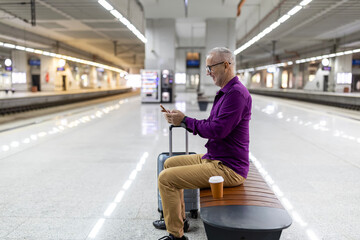 Senior man using smartphone waiting for train