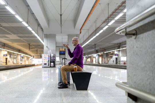 Mature man conversing on phone at modern train station
