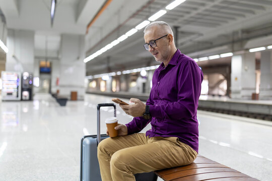 Man waiting at subway station using smartphone