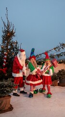 Naklejka premium Santa Claus with elves in a festive Christmas scene with a hammer