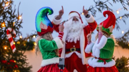 Santa Claus and elves pointing up while filming a video outdoors