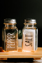 Salt and pepper shakers on a wooden table against a dark background in a cozy setting