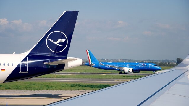 Fiumicino Airport, Rome, Italy, Europe - April 3, 2025 - Lufthansa aircraft tail and wing in foreground with an ITA Airways Airbus A320neo taxiing, representing air travel and international connection
