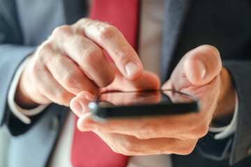 Close up of businessman hands using smartphone, index finger tapping on touchscreen.