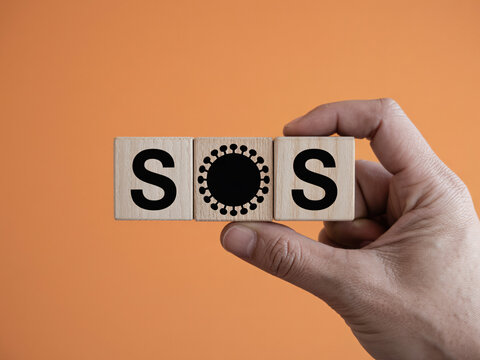 Urgent SOS message about health crisis conveyed with letter blocks in hand, sending a powerful signal for help and awareness on medical emergency