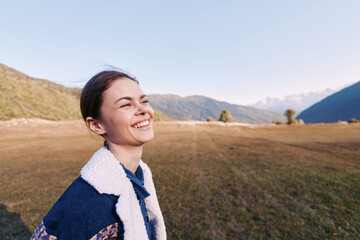Fototapeta premium Woman smile portrait mountains meadow nature outdoor happiness captured in candid closeup of young female wearing fleece jacket at sunrise in scenic valley landscape enjoying freedom.