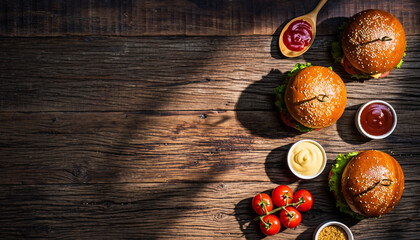 Delicious homemade burgers on rustic wood table, ready for a backyard barbecue or casual dining experience with fresh tomatoes and condiments