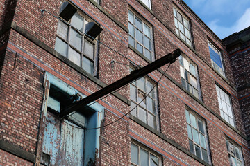 Old red brick building with many windows and a metal element extending from one in Mutual Mills - Heywood - Greater Manchester - UK
