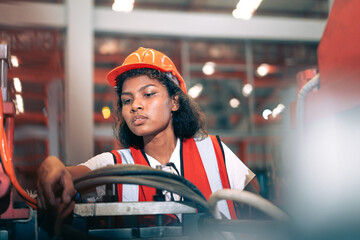 Professional Black African female factory engineer/worker/technician operate machinery in modern industrial plant. She wear safety helmet,vest show focus,skill in repair maintenance production process