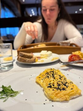 Tortilla francesa premium en un plato decorado y una mujer desayunando 