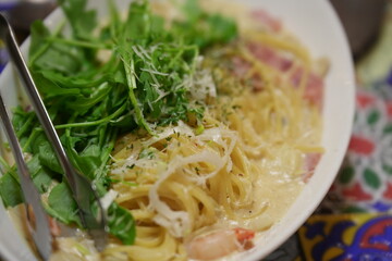 Creamy carbonara-style pasta with pancetta, fresh arugula and parmesan shavings – gourmet close-up